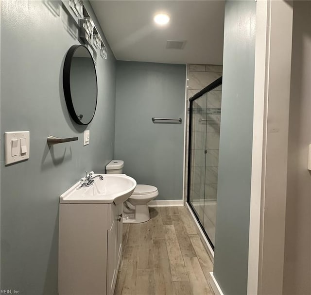 bathroom with vanity, wood finished floors, toilet, and a shower stall