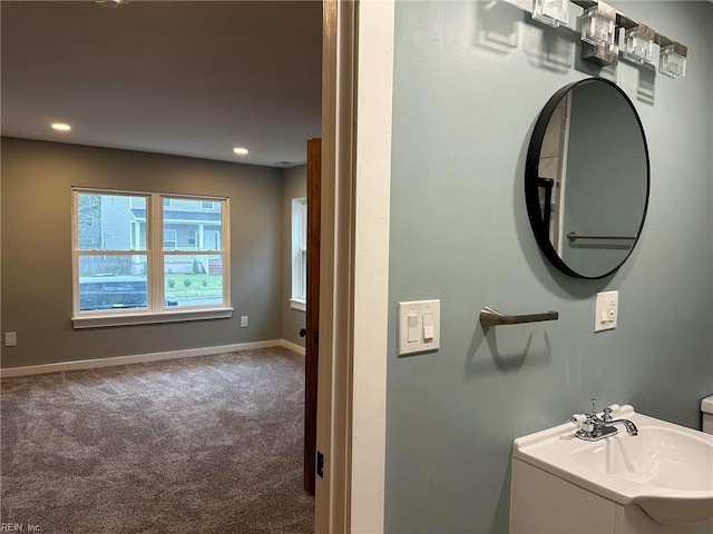 bathroom featuring recessed lighting, a sink, and baseboards