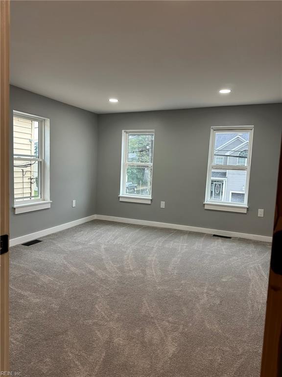 carpeted empty room featuring recessed lighting, visible vents, and baseboards