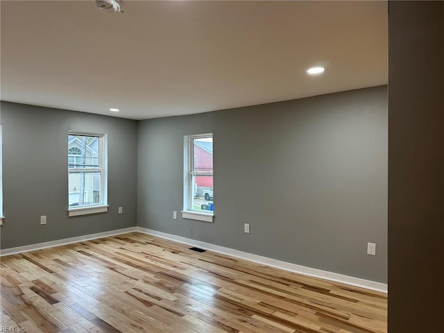 unfurnished room featuring plenty of natural light, light wood-style flooring, and baseboards