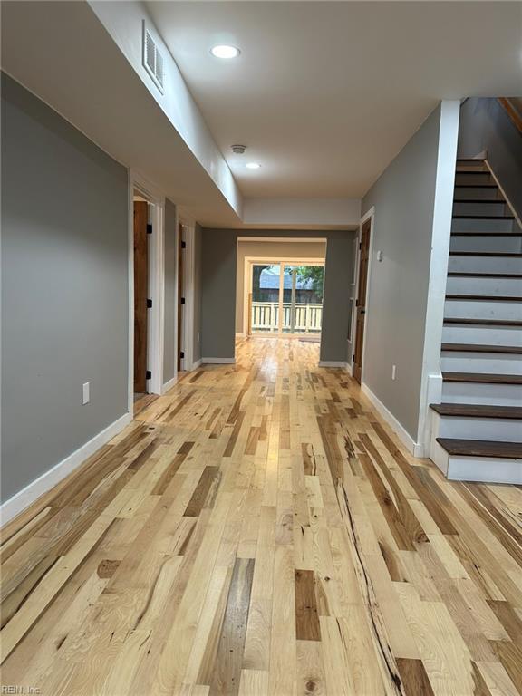 hallway featuring light wood finished floors, recessed lighting, visible vents, baseboards, and stairs