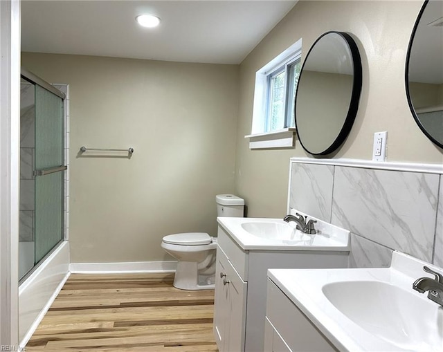 full bath featuring two vanities, a sink, toilet, and wood finished floors