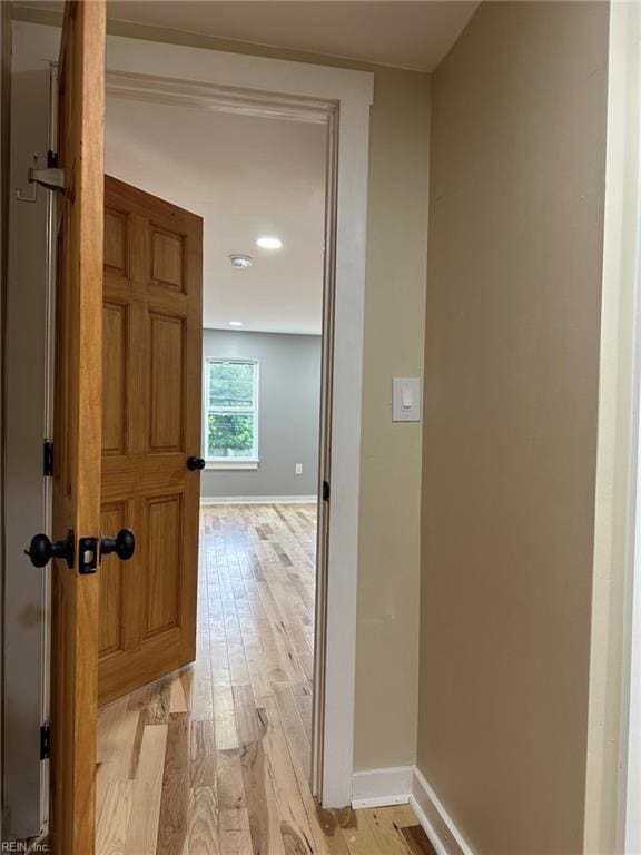 hallway with light wood-type flooring and baseboards