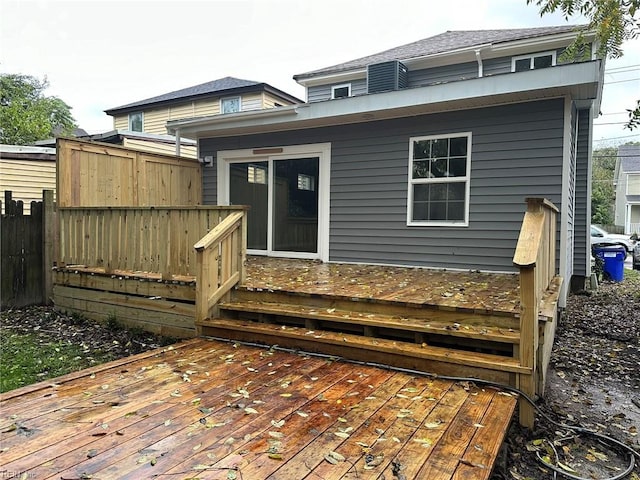 rear view of house featuring a deck and fence