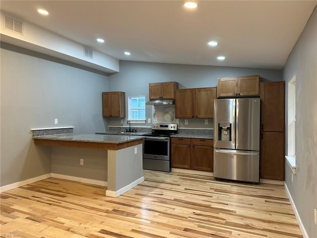 kitchen featuring lofted ceiling, under cabinet range hood, visible vents, and appliances with stainless steel finishes