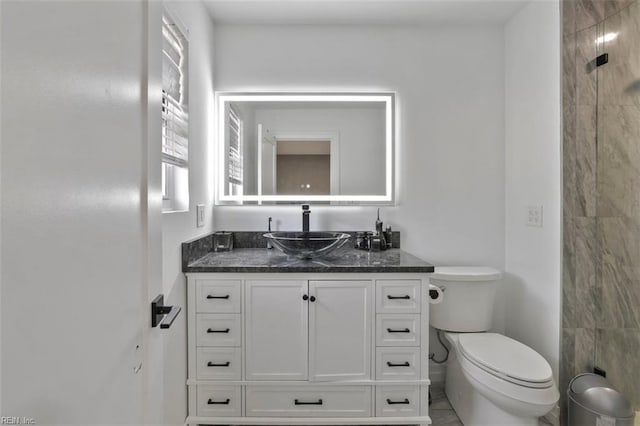 bathroom featuring tiled shower, vanity, and toilet