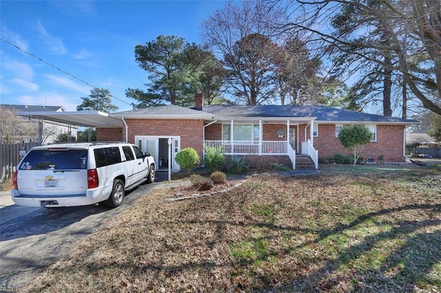 ranch-style house featuring covered porch, a chimney, an attached carport, and brick siding