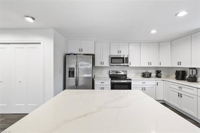 kitchen featuring light stone counters, dark wood-style floors, recessed lighting, appliances with stainless steel finishes, and white cabinets