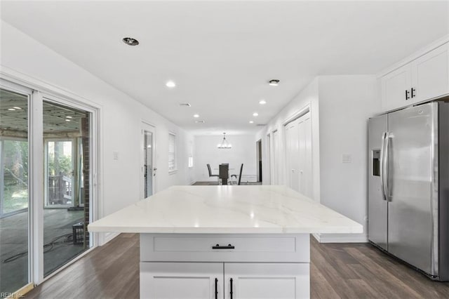 kitchen featuring stainless steel fridge, white cabinets, a kitchen island, light stone counters, and dark wood-style flooring