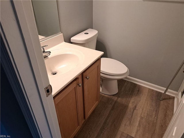 bathroom featuring toilet, baseboards, wood finished floors, and vanity