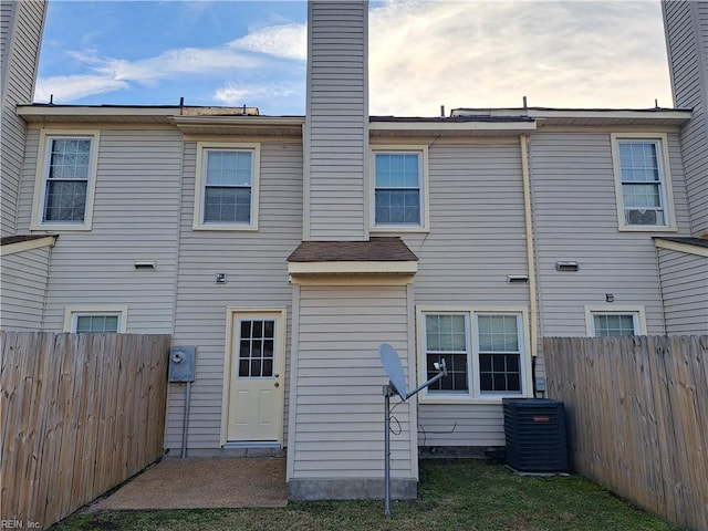 rear view of property featuring central AC, fence, and a chimney