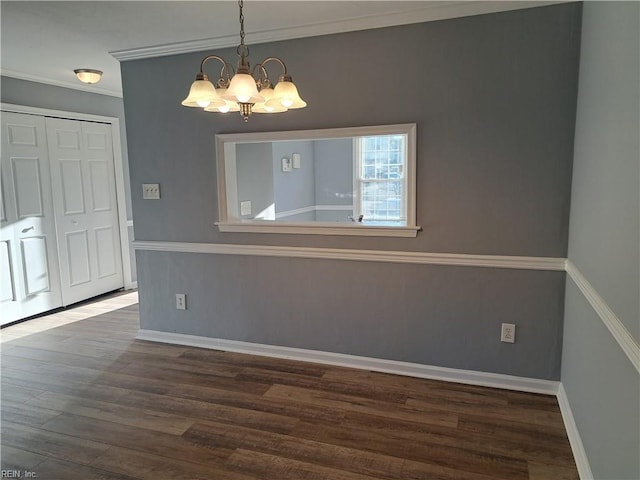 unfurnished dining area with ornamental molding, a chandelier, baseboards, and wood finished floors