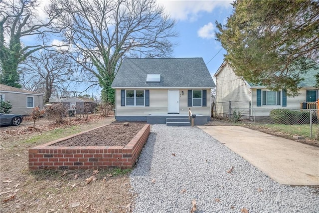 view of front of property featuring driveway, fence, and roof with shingles