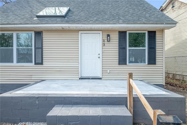 entrance to property featuring roof with shingles