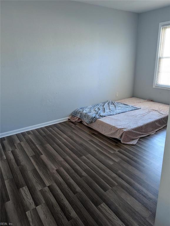 unfurnished bedroom featuring dark wood-type flooring and baseboards