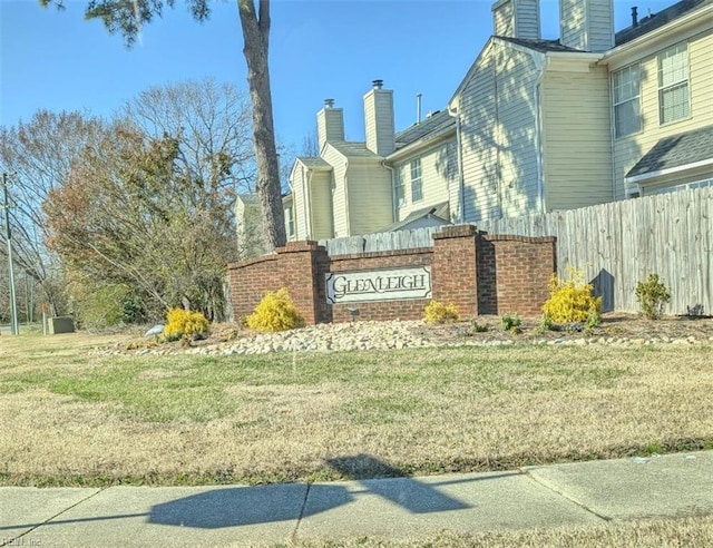 community / neighborhood sign featuring a lawn and fence