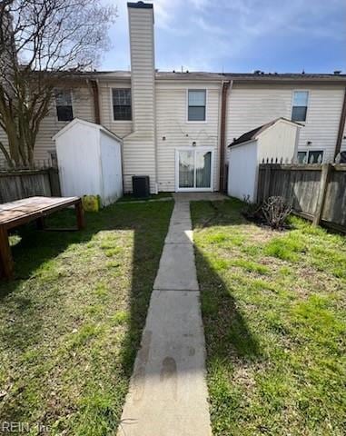 rear view of property with fence, a lawn, and a chimney