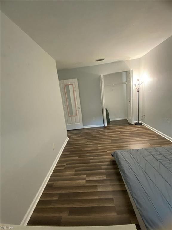 corridor featuring visible vents, baseboards, and dark wood finished floors