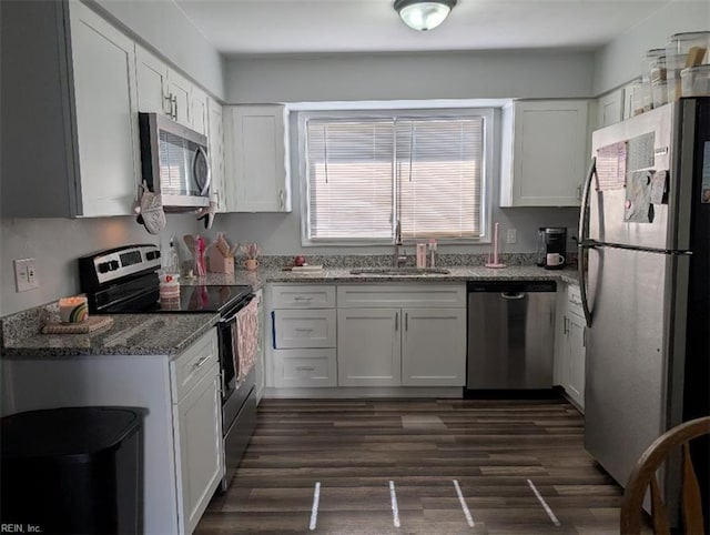 kitchen featuring a sink, light stone counters, dark wood finished floors, white cabinetry, and stainless steel appliances