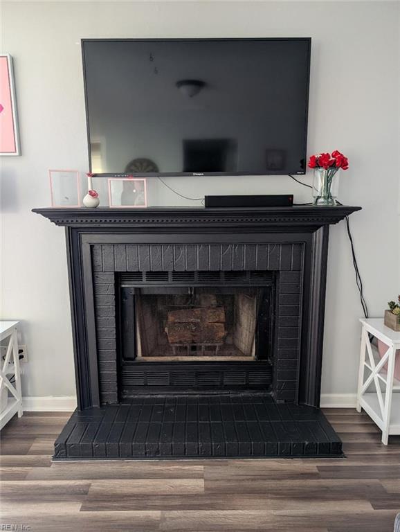 interior details featuring baseboards, a brick fireplace, and wood finished floors