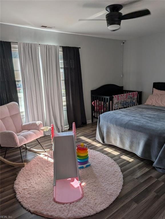 bedroom featuring ceiling fan, visible vents, multiple windows, and wood finished floors