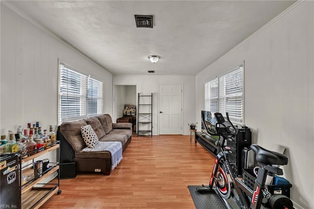 workout room with ornamental molding, visible vents, plenty of natural light, and light wood-style flooring