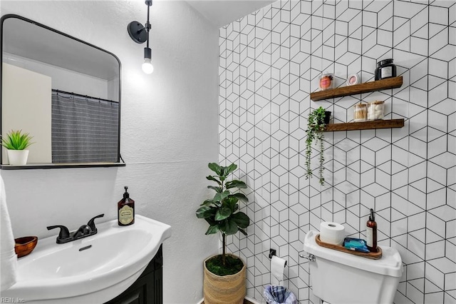 bathroom featuring toilet, tile walls, and vanity