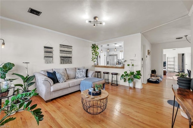 living area with ornamental molding, light wood-style flooring, and visible vents