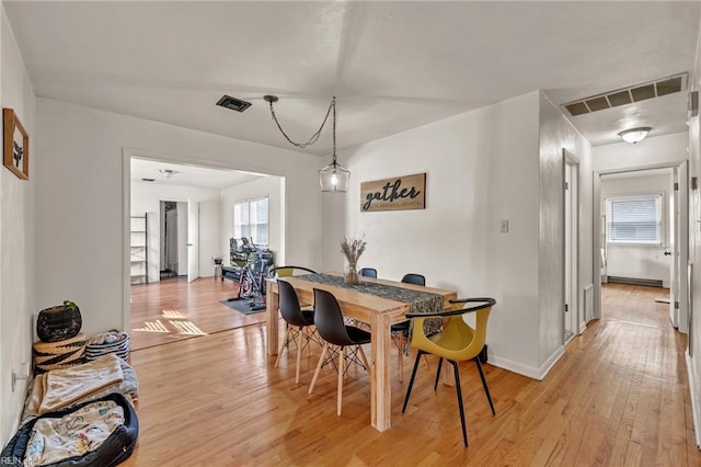 dining area featuring baseboards, visible vents, and light wood finished floors