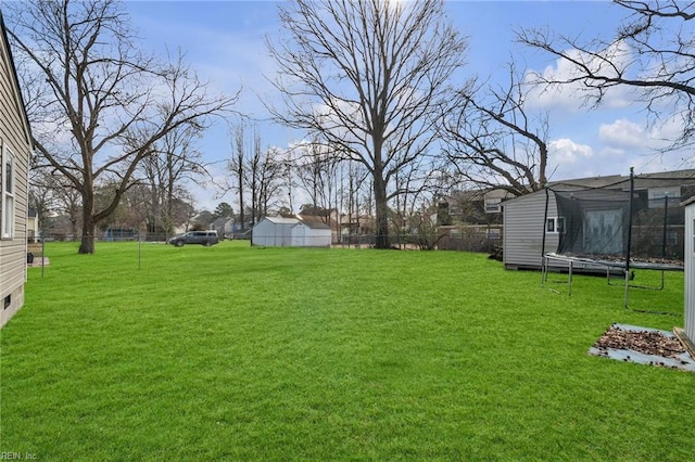 view of yard with a trampoline and fence