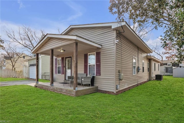 view of front of property with covered porch, concrete driveway, central AC unit, a garage, and a front lawn