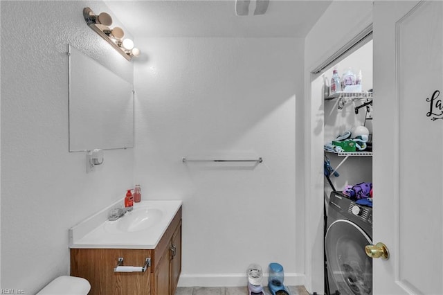 bathroom with washer / clothes dryer, vanity, and baseboards