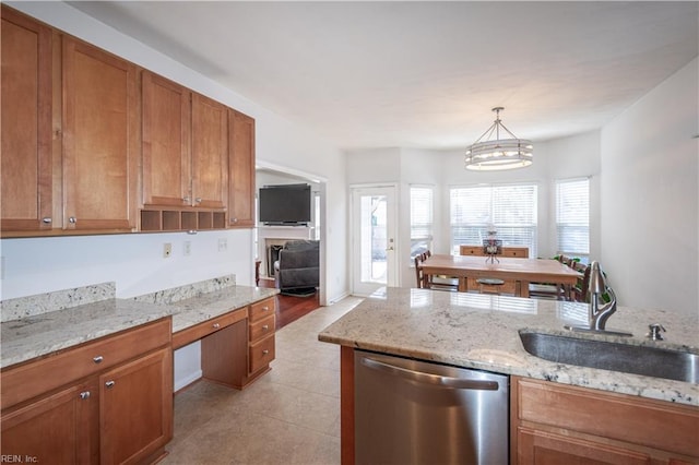 kitchen featuring brown cabinets, dishwasher, hanging light fixtures, and a sink