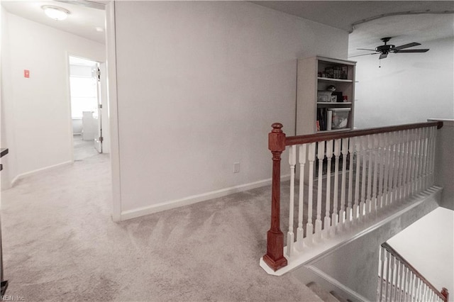 hall with baseboards, carpet flooring, and an upstairs landing