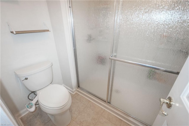 full bathroom featuring a stall shower, baseboards, and toilet