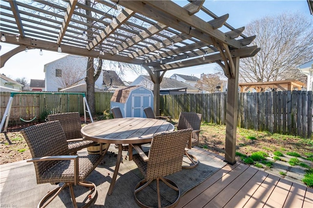 view of patio / terrace with a fenced backyard, an outbuilding, a shed, a pergola, and outdoor dining space