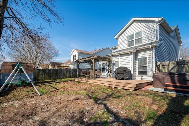 back of property with a hot tub, a fenced backyard, a pergola, and a wooden deck