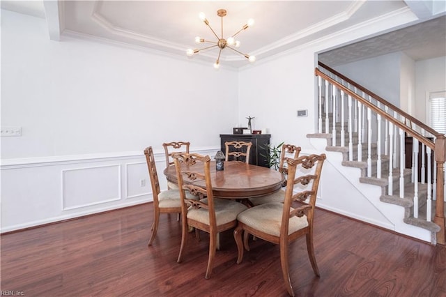 dining space featuring a raised ceiling, crown molding, an inviting chandelier, and wood finished floors