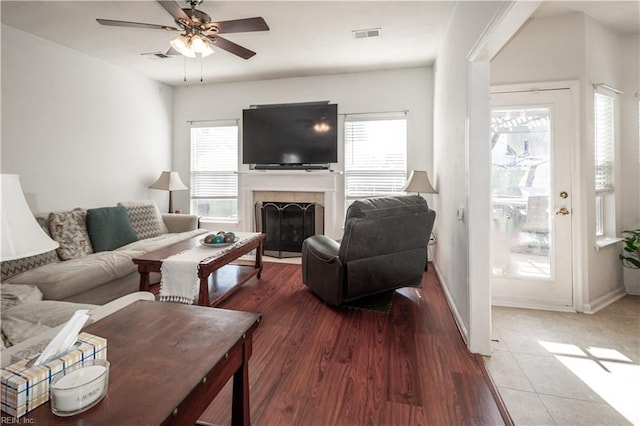 living area featuring light wood-type flooring, plenty of natural light, a fireplace, and visible vents