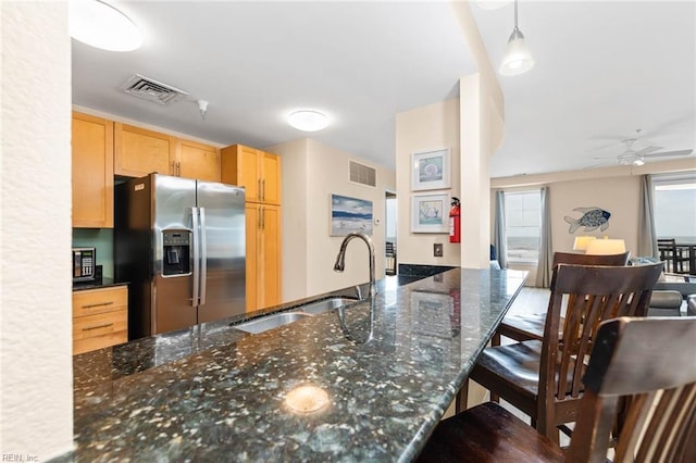 kitchen with visible vents, light brown cabinetry, a sink, and stainless steel fridge with ice dispenser