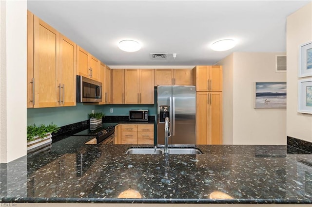 kitchen featuring black appliances, dark stone countertops, a sink, and visible vents