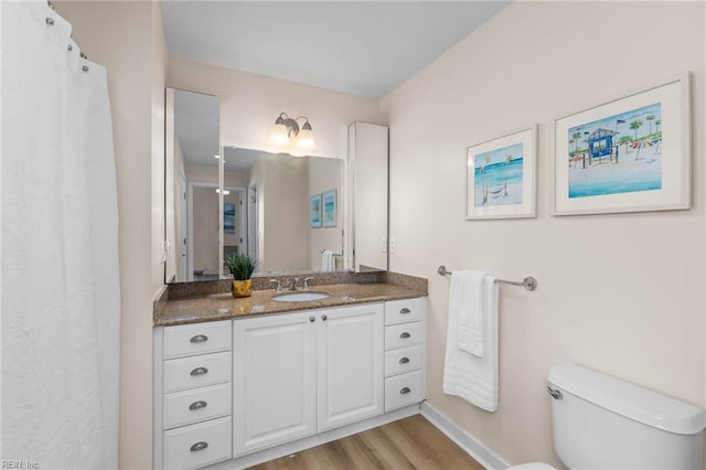 bathroom featuring toilet, wood finished floors, and vanity