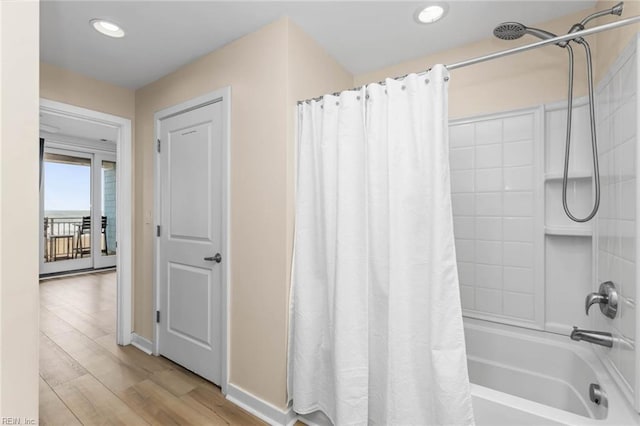 bathroom featuring baseboards, shower / tub combo, wood finished floors, and recessed lighting