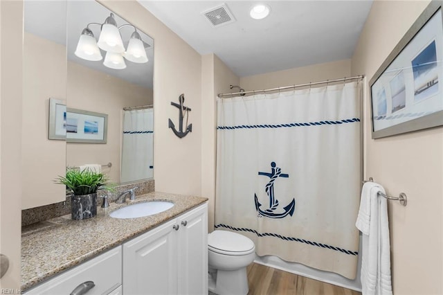 bathroom with visible vents, toilet, an inviting chandelier, vanity, and wood finished floors