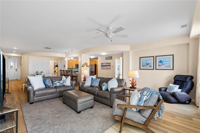 living area featuring light wood finished floors, ceiling fan, and visible vents