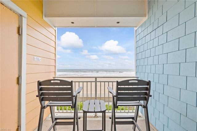 balcony featuring a view of the beach and a water view