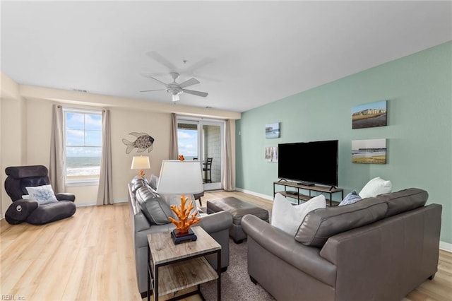 living room featuring baseboards, ceiling fan, and light wood finished floors