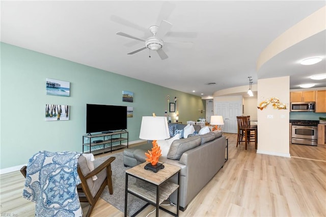 living room featuring light wood-type flooring, a ceiling fan, and baseboards