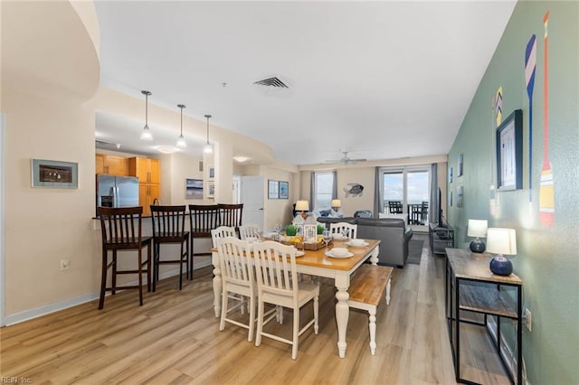 dining space with light wood finished floors, baseboards, visible vents, and ceiling fan