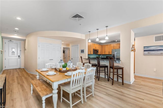 dining space featuring light wood-type flooring, visible vents, and baseboards